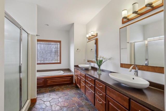 full bath with double vanity, a sink, a garden tub, and a stall shower