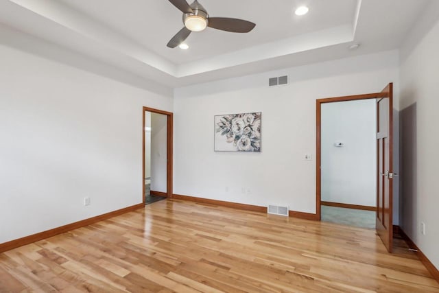 spare room with visible vents, a raised ceiling, and light wood-style floors