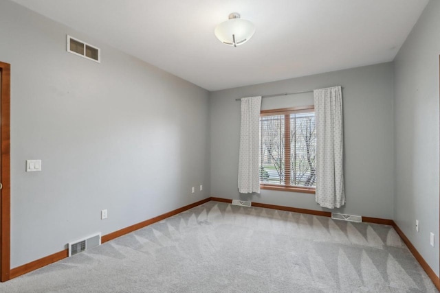 carpeted spare room featuring baseboards and visible vents