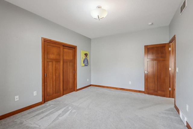 unfurnished bedroom featuring baseboards, visible vents, light carpet, and a closet