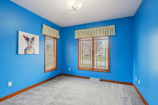 unfurnished room with carpet floors, baseboards, visible vents, and a healthy amount of sunlight