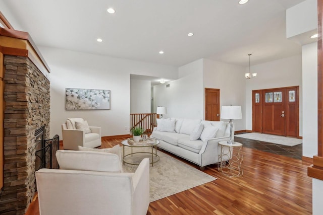 living area featuring recessed lighting, a stone fireplace, and wood finished floors