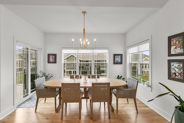 dining space with baseboards, a chandelier, and light wood-style floors