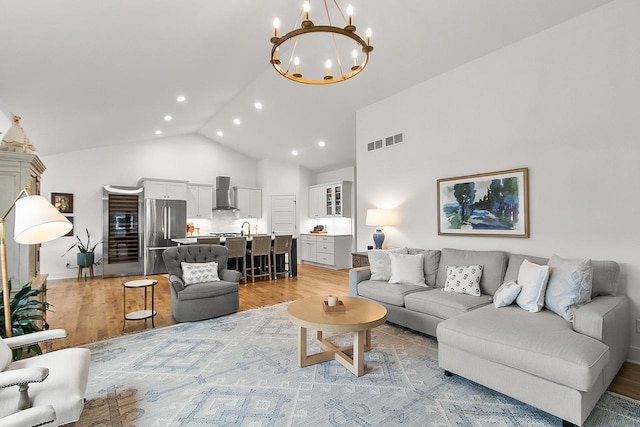 living area with high vaulted ceiling, a chandelier, light wood-style flooring, recessed lighting, and visible vents