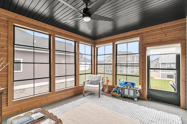 sunroom / solarium with wooden walls and carpet