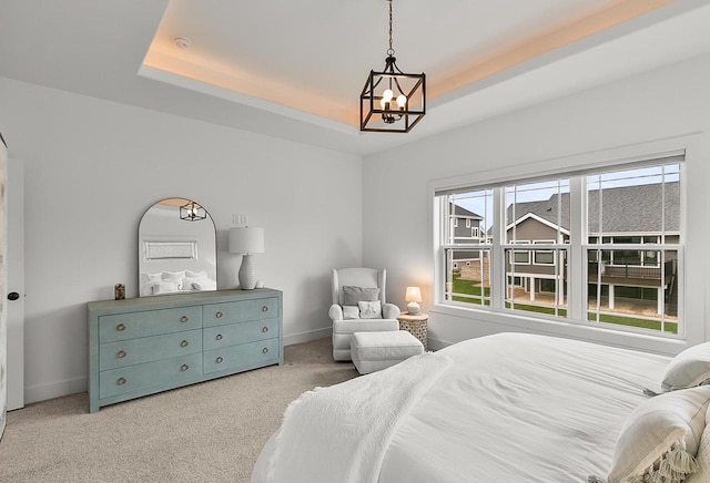 bedroom with a tray ceiling, baseboards, light colored carpet, and a notable chandelier