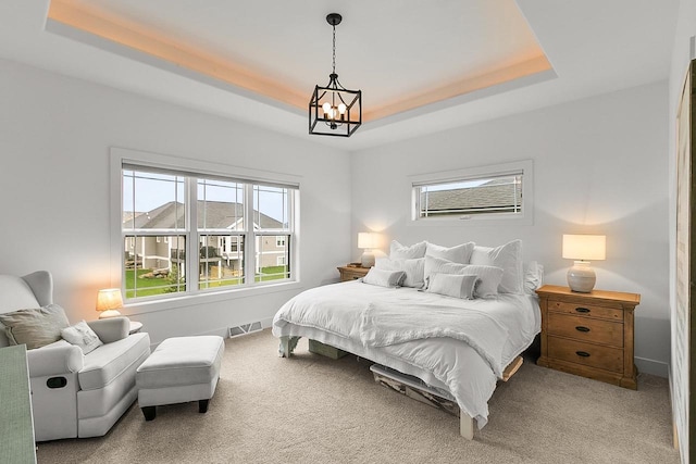 carpeted bedroom featuring visible vents, baseboards, a tray ceiling, and a chandelier