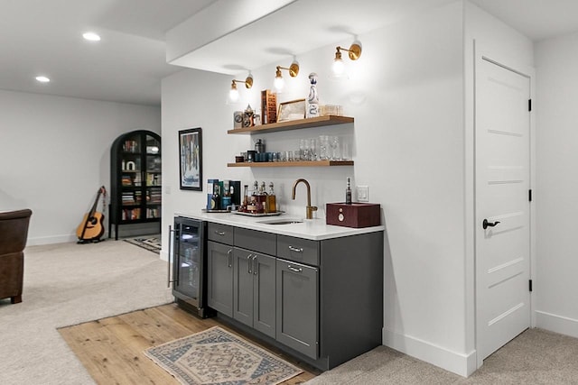 bar with beverage cooler, wet bar, light colored carpet, and a sink