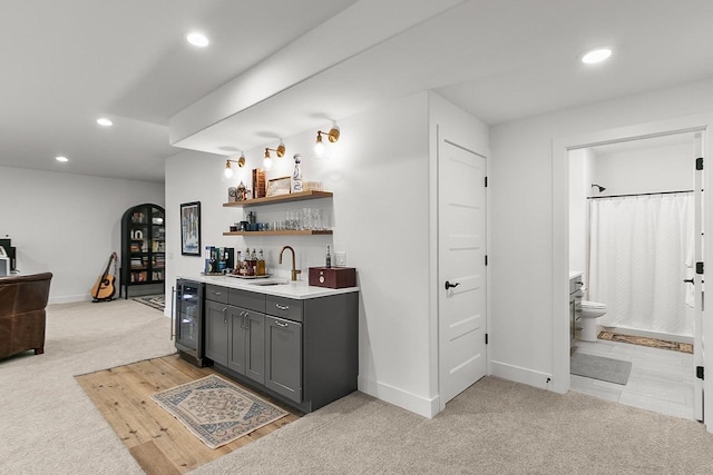 bar with light carpet, beverage cooler, recessed lighting, a sink, and wet bar