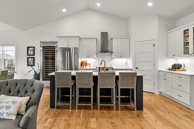 kitchen featuring freestanding refrigerator, wall chimney exhaust hood, tasteful backsplash, and light countertops