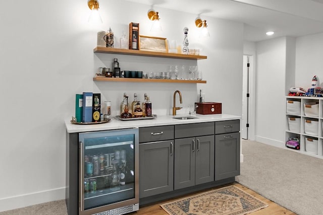 bar featuring wet bar, a sink, baseboards, wine cooler, and light carpet
