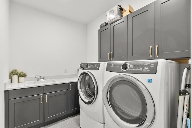 washroom featuring a sink, cabinet space, light tile patterned flooring, and washing machine and clothes dryer