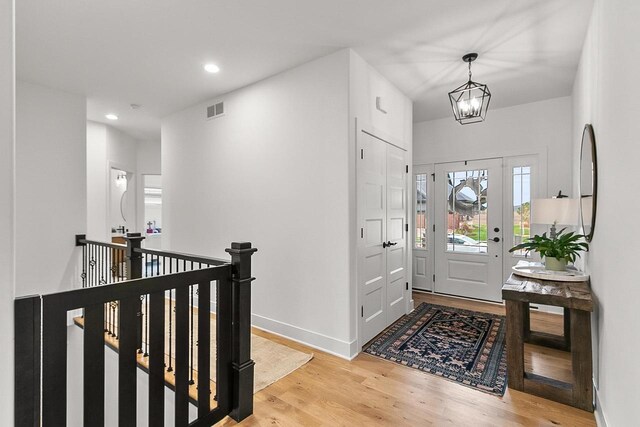 foyer entrance with visible vents, baseboards, light wood finished floors, a notable chandelier, and recessed lighting