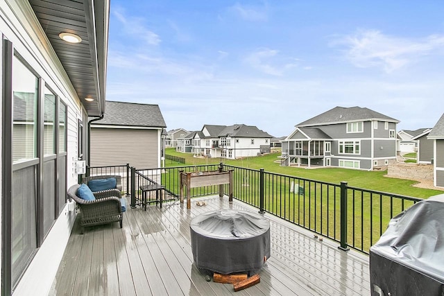 wooden deck featuring a residential view, a lawn, and area for grilling