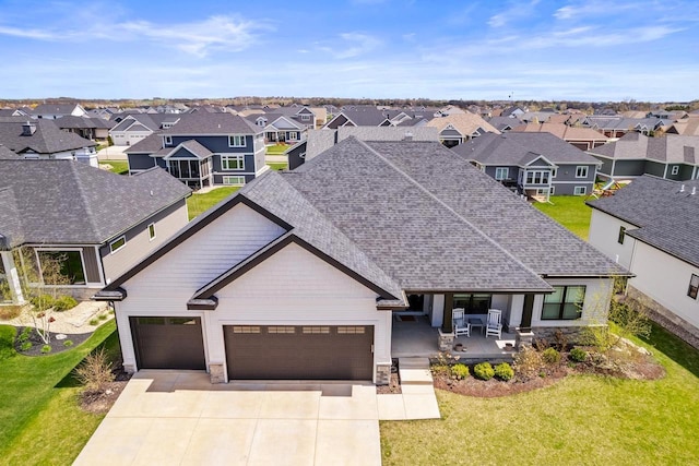 view of front of property featuring a residential view, a front lawn, a garage, covered porch, and driveway