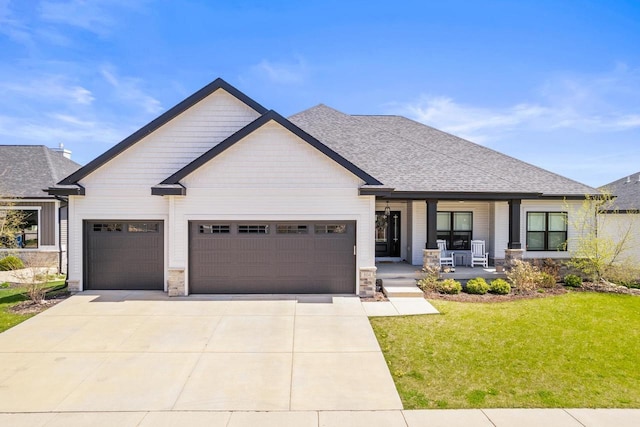 view of front of house with a front lawn, stone siding, a garage, a porch, and concrete driveway