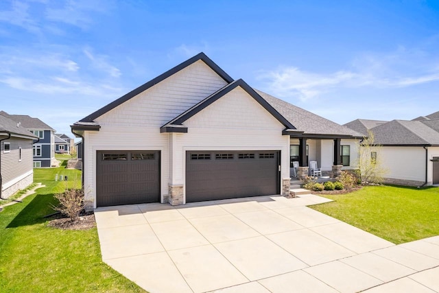 view of front of home featuring stone siding, an attached garage, driveway, and a front yard