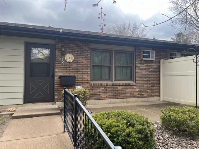 entrance to property with brick siding and fence