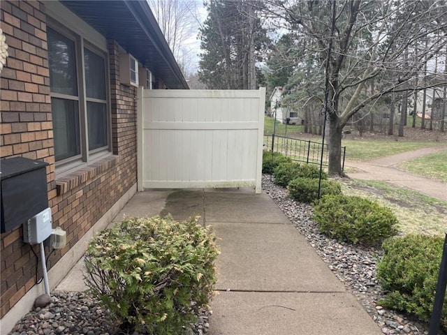 view of property exterior featuring brick siding and fence