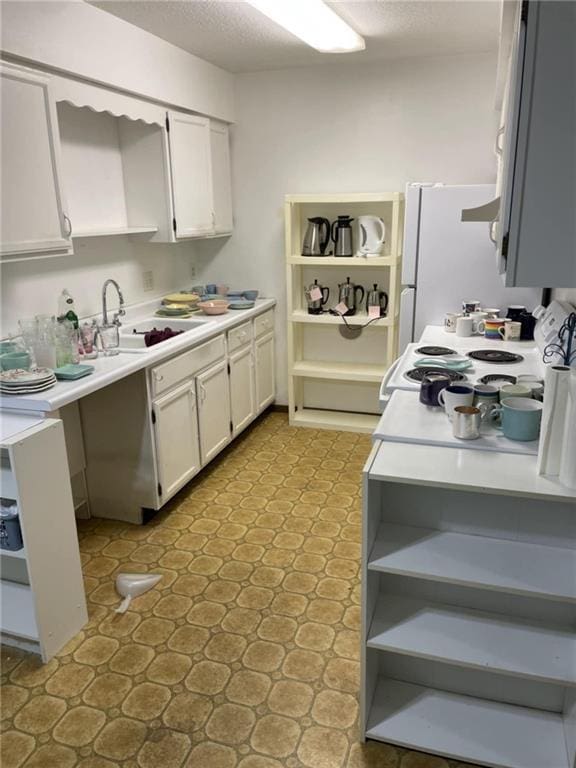 kitchen featuring open shelves, stove, a sink, light countertops, and white cabinetry