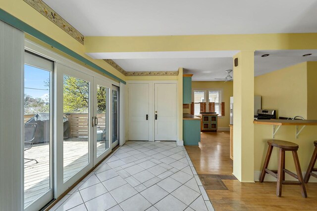 doorway to outside with baseboards, ceiling fan, light wood-type flooring, and beam ceiling