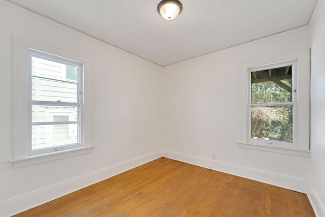 spare room with baseboards and light wood-style flooring