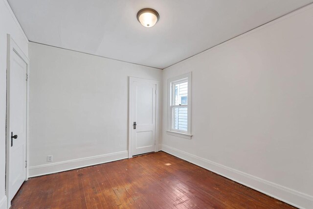 spare room with wood-type flooring and baseboards