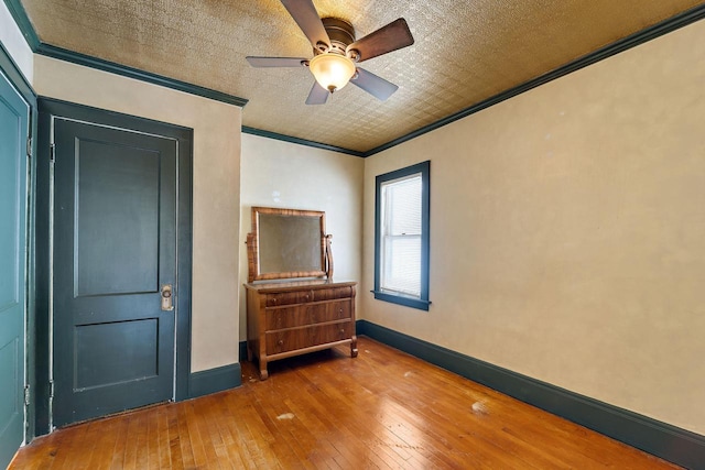 bedroom with crown molding, baseboards, wood-type flooring, and a ceiling fan
