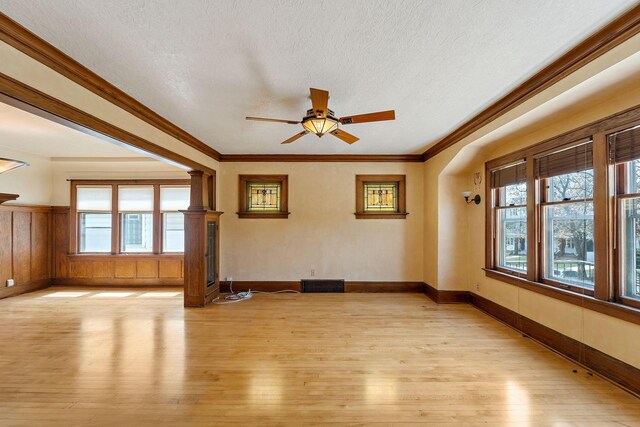 unfurnished room with a textured ceiling, plenty of natural light, ceiling fan, and light wood-type flooring