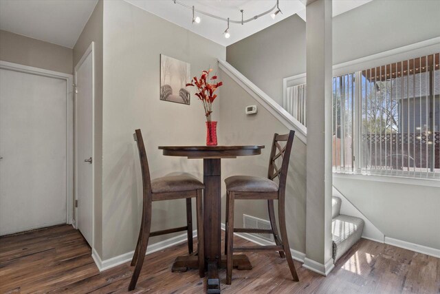 dining area with baseboards, visible vents, wood finished floors, and stairway