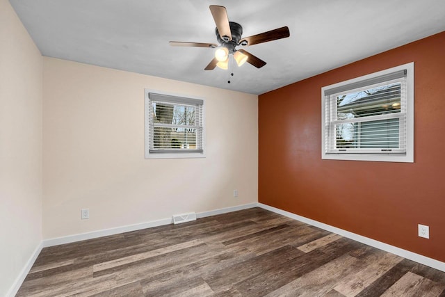 unfurnished room featuring visible vents, a ceiling fan, baseboards, and wood finished floors