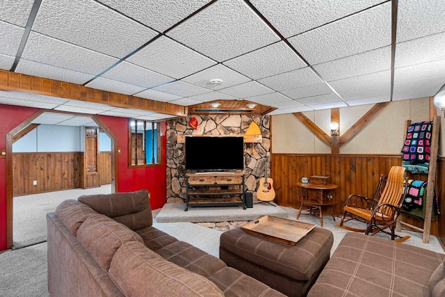 carpeted living area featuring wainscoting, wooden walls, and a paneled ceiling
