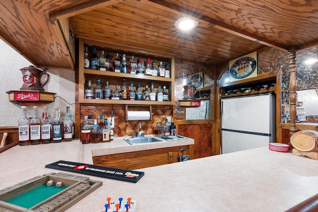bar with a sink, wooden ceiling, freestanding refrigerator, and wet bar