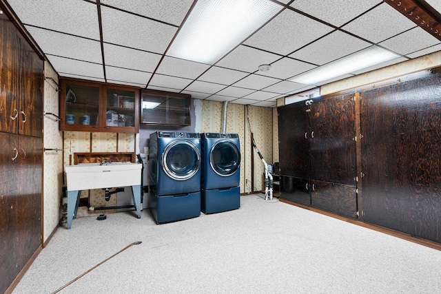 laundry area with laundry area, washing machine and dryer, a sink, carpet floors, and wallpapered walls