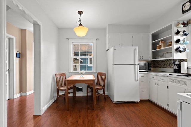 kitchen featuring freestanding refrigerator, stainless steel microwave, dark wood finished floors, and white cabinets