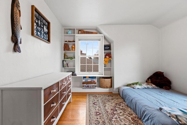 bedroom with vaulted ceiling and light wood-type flooring