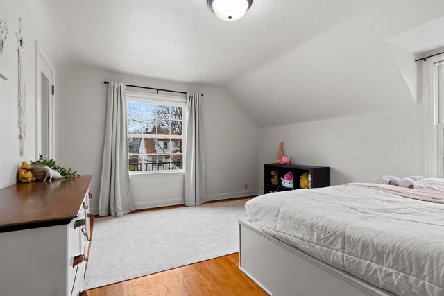 bedroom featuring light wood-style flooring and lofted ceiling