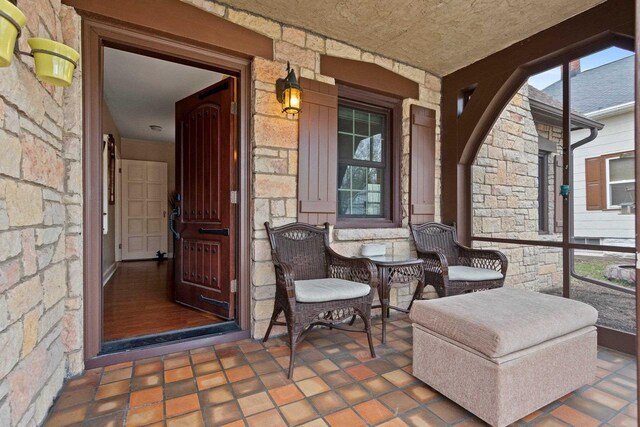 doorway to property with covered porch and stone siding