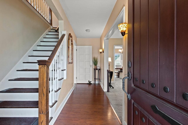foyer entrance with baseboards, stairs, and dark wood-style flooring
