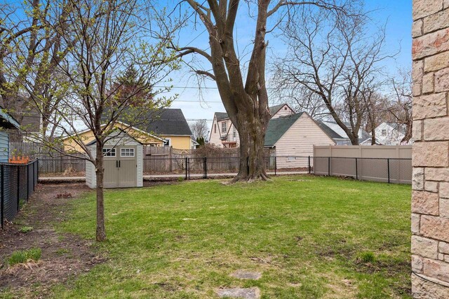 view of yard featuring a fenced backyard, a storage unit, and an outbuilding
