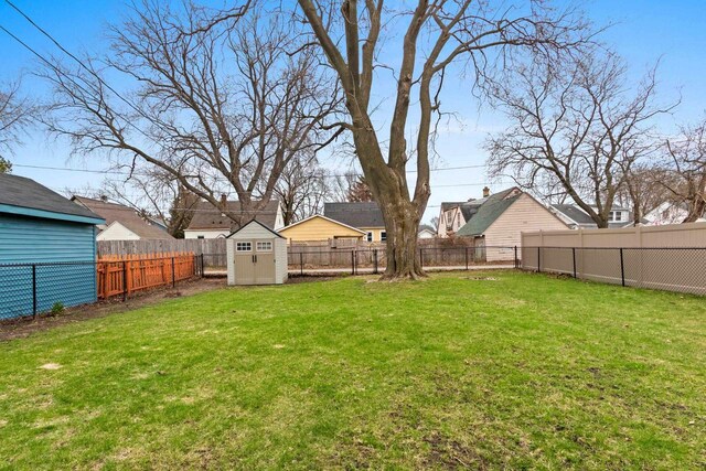 view of yard with a fenced backyard, an outbuilding, and a shed