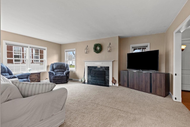 carpeted living area featuring baseboards and a fireplace