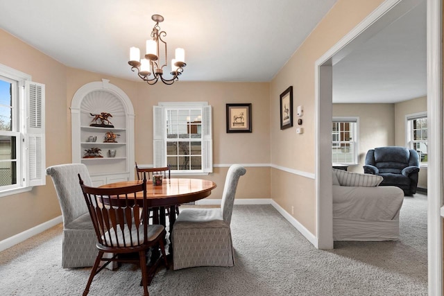 dining space featuring baseboards, a chandelier, and carpet