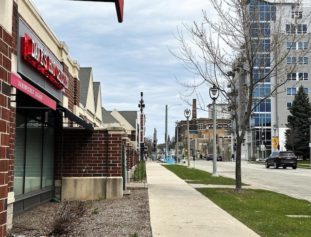 view of street featuring sidewalks, traffic signs, street lighting, and curbs