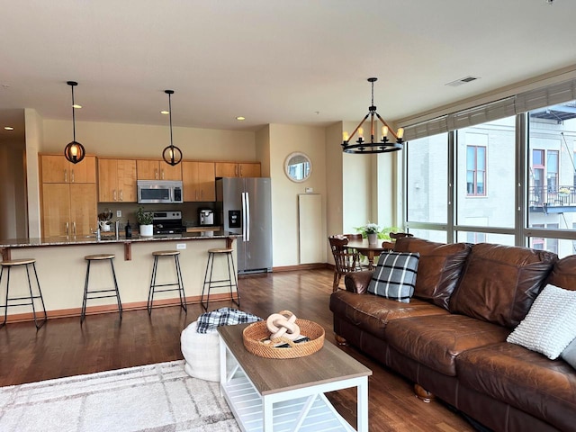 living area with visible vents, baseboards, a notable chandelier, and dark wood-style floors