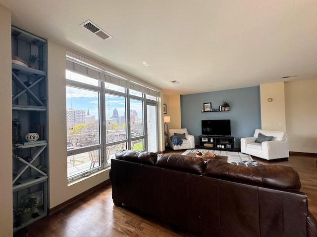 living area with baseboards, plenty of natural light, dark wood-style floors, and visible vents