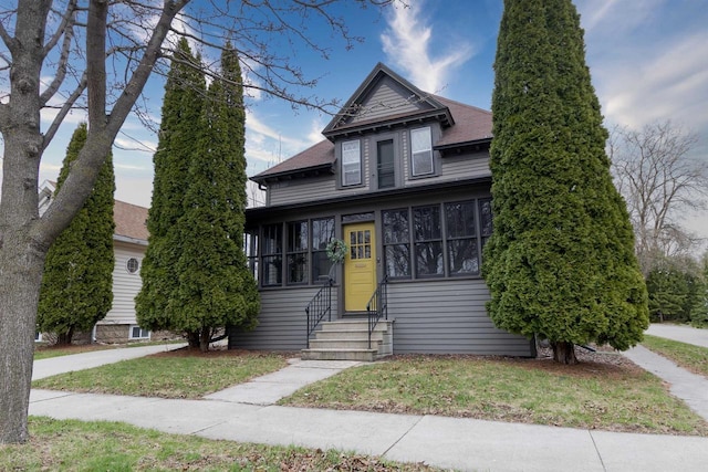 bungalow featuring a front yard, a shingled roof, and entry steps