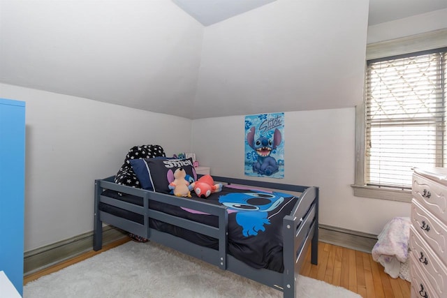 bedroom featuring wood finished floors and lofted ceiling