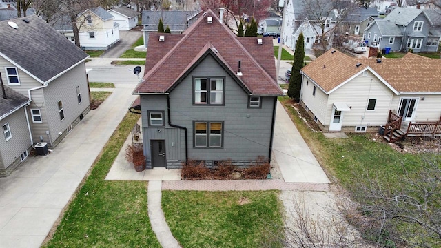 view of front of home featuring a residential view, cooling unit, and a front yard