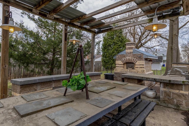 view of patio / terrace with an outdoor fireplace, fence, and a pergola